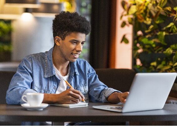 Young teen blogger making notes for new publication at cafe