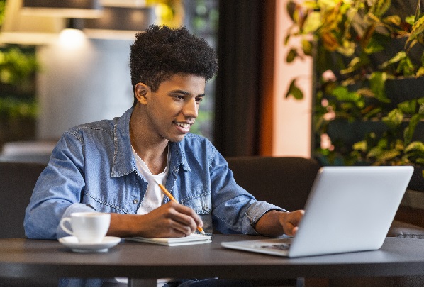 Young teen blogger making notes for new publication at cafe